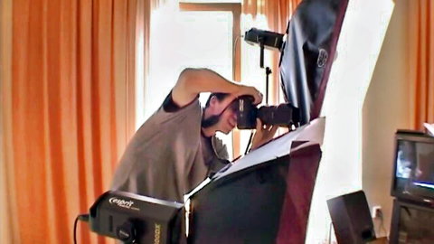 Behind the scenes photographer adjusting Godox lights and camera during adult video shoot