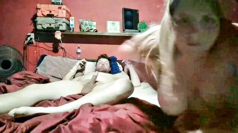 Naked man legs spread on bed exposing cock as blurred woman's hand strokes him