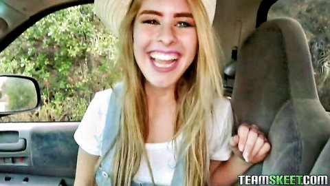Lilly Ford smiling in car, blonde in white top and overalls, outdoor vibe