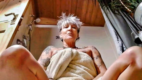 Tattooed granny spreads legs wide in towel teasing pussy in bathroom