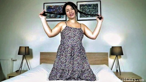 Brunette babe playfully lifting long black hair in floral dress teasing in bedroom