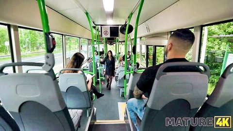 Brunette MILF in short dress struts down public bus aisle teasing tattooed guys for rough sex