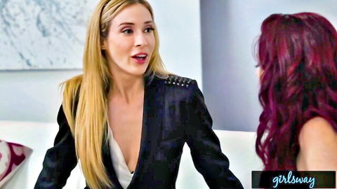 Blonde agent in cleavage-revealing blazer talks intently to redhead beauty on couch