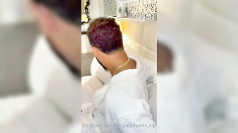 Muscular man in open white robe from behind, curly red hair, gold chain, OnlyFans tease
