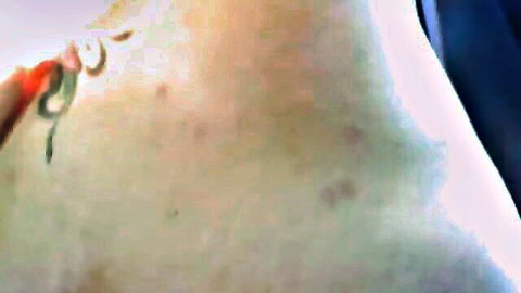 Closeup of sexy snake tattoo on pale freckled skin with red nails tracing it in car backseat