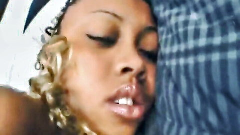 Close-up of black woman with blonde curls, eyes closed in pleasure