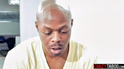 Bald Black man in light robe, intense gaze in Jesse Pony DP scene