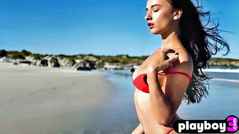 Petite brunette with big breasts posing in red bikini on beach