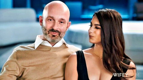 Bald bearded husband and busty brunette wife in teasing pose