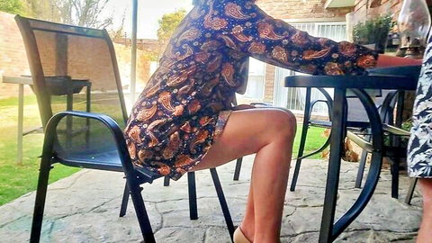 Brunette in short patterned dress sitting outdoors with legs apart, neighbor wife tease