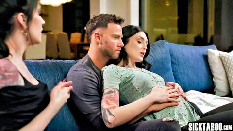 Tattooed man hugs pregnant brunette woman as dark-haired instructor watches intimately