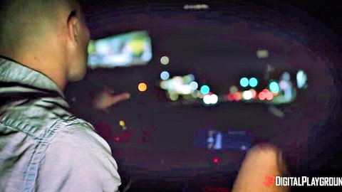 Bald man driving luxury car through blurred city lights at night