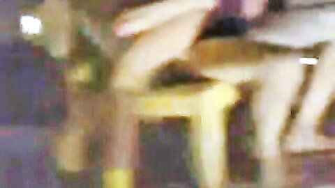 Blurry amateur view of nude woman spreading legs wide on yellow stool with hands on thighs