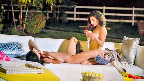 Two busty naked brunettes with big natural tits and trimmed pussies lounging on outdoor sofa
