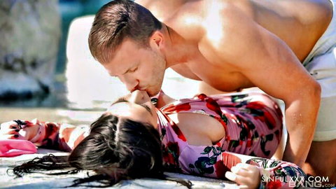 Muscular stud passionately kisses busty babe in floral swimsuit on sunny beach