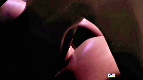 Close-up of voluptuous pinkish curves and breasts in dark lighting