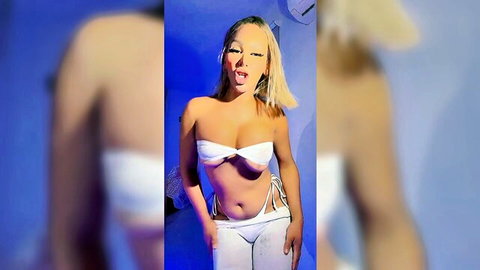 Blonde trans babe in skimpy white bikini top and thong posing seductively with tongue out