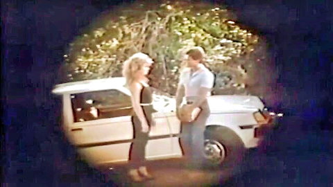 Traci Lords in 80s outdoor flirt with man by white car