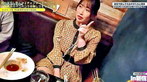 Japanese woman in patterned dress pointing at camera in restaurant