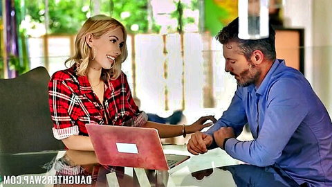 Blonde woman in open plaid shirt smiles intimately at bearded man over laptop