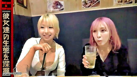 Blonde and pink-haired Asian women in revealing tops at bar, smiling