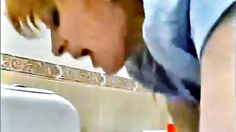 Blonde woman drooling thick cum from wide open mouth over bathroom sink