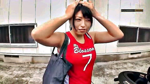 Frustrated Asian woman in red basketball jersey gripping head outdoors
