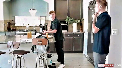 Two young men in casual shirts bonding intimately in a modern kitchen