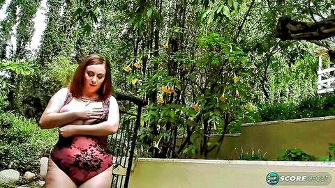Curvy redhead MILF with huge tits cups breasts in red lace lingerie outdoors