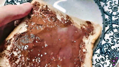 Hand pressing thick gooey chocolate spread on white toast bread closeup