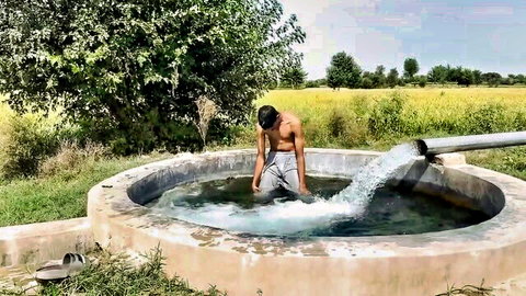 Sexy shirtless Pakistani hunk bending over rural well in low gray sweatpants teasing muscular back