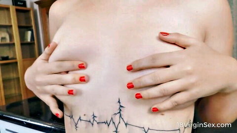 Topless woman with heartbeat tattoo covers breasts with hands