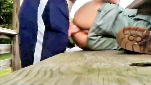 Two men in outdoor anal sex, one penetrating ass on wooden bench