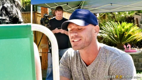 Bald stud smiles poolside with brunette babe and camera crew in Brazzers outdoor shoot