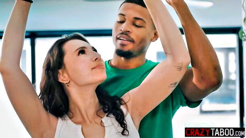 Liz Jordan with muscular black man, arms raised in intimate gym pose