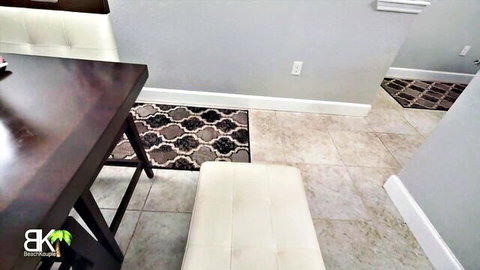 Empty gray bathroom interior with dark wood table white ottoman and patterned rugs