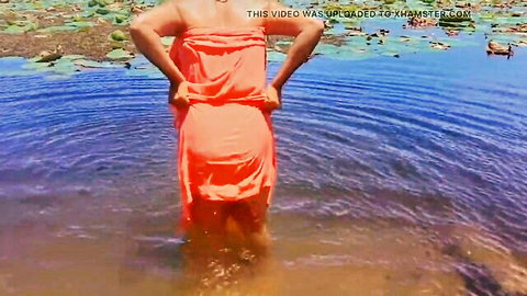 Sri Lankan girl in wet orange dress bathing in outdoor pond