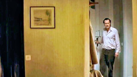 Middle-aged man in light shirt and trousers walking down yellow hallway