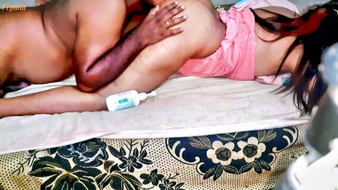 Dark-skinned man gropes light-skinned woman's bare ass with lube bottle nearby on bed