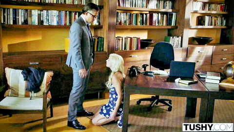 Blonde in floral dress kneels before suited man in library office ready for blowjob
