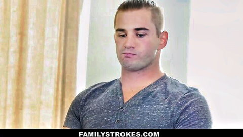 Young muscular guy in gray V-neck shirt looking down seriously on familystrokes