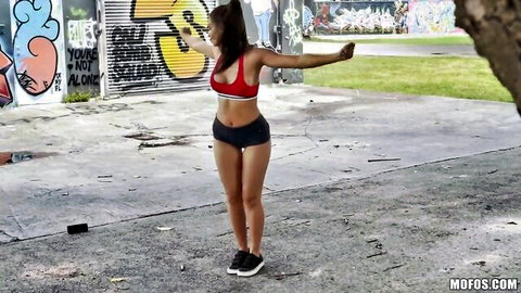 Asian athletic woman in red sports bra and black shorts posing outdoors