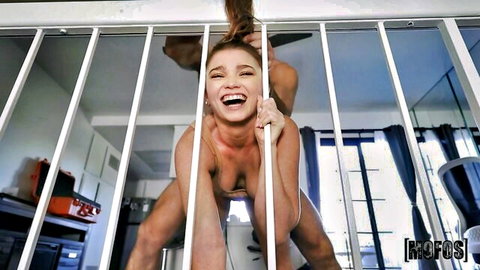 Tanned athletic woman smiling nude gripping balcony rails spreading legs exposing shaved pussy and perky tits