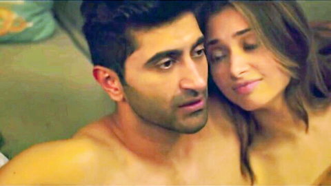 Shirtless muscular Indian man embraces busty woman's cleavage in steamy intimate bedroom gaze