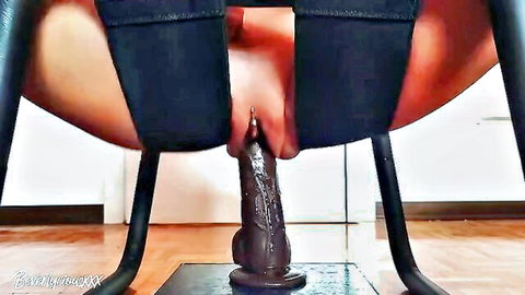 Woman riding large dildo reverse cowgirl style, explicit penetration visible