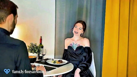 Beautiful brunette in sexy off-shoulder black dress laughing seductively with man at romantic candlelit dinner