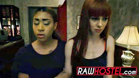 Ebony and redhead women in tank tops with shocked expressions in hostel