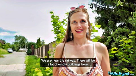 Smiling blonde in low-cut colorful tank top outdoors near railway, Public Agent scene