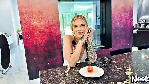 Blonde with tattoos and small tits teases deep cleavage smiling in kitchen holding phone