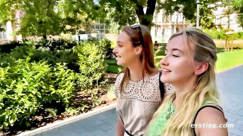 Two smiling amateur babes with small tits walking hand-in-hand outdoors in park